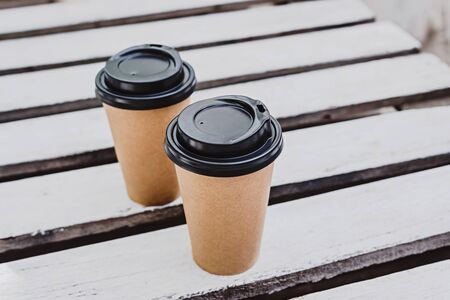 Two paper coffee cups to go on white wooden plank background with copy space.の写真素材