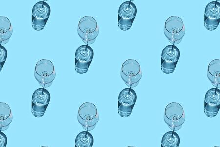 Pattern made of empty wine glasses with shadow on blue background. Top view, flat lay.の写真素材