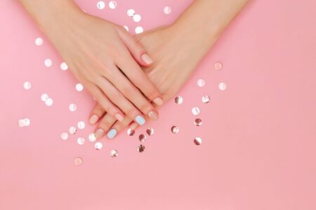Woman's hands with pastel manicure on pink background with copy space and confetti. Top view.の写真素材