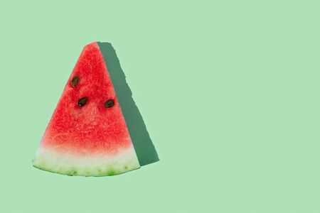 Slice of ripe watermelon on mint green background with copy space. Flat lay, top view.の写真素材