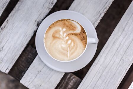 White big cup of coffee with art on white wooden table with copy space. Close up.の写真素材