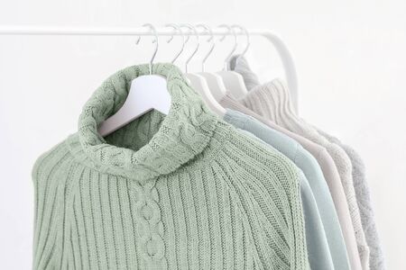 Tranquil mint green knitted warm sweaters on white hangers. Close up.の写真素材
