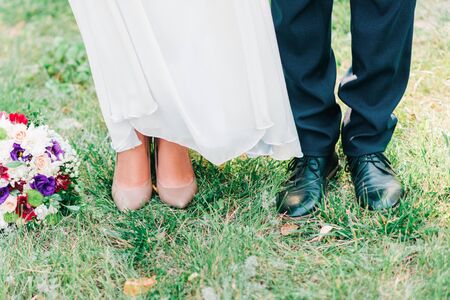 Cute cropped picture of groom's and bride's shoes standing together on the grass. Top view.の写真素材