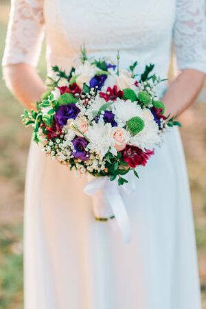 Hands of bride with wedding beautiful bouquet of white, purple and pink flowers.の写真素材