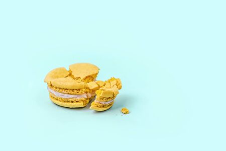 Crushed yellow macaroon on pastel blue background with copy space. Top view.