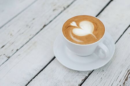White big cup of coffee with shaped heart art on white wooden table with copy space. Top view.の写真素材