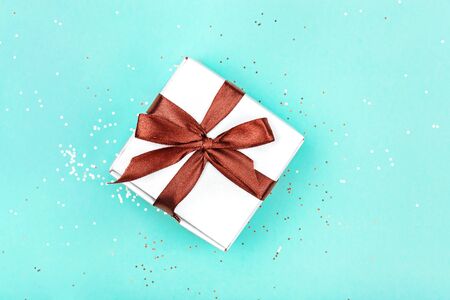 Gift box with brown bow on green mint background with delicate golden sparkles. Top view.の写真素材