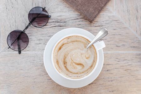 White big cup of delicious coffee and round sunglasses on wooden table with copy space. Top view.の写真素材