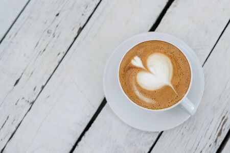 White big cup of delicious coffee with shaped heart art on white wooden table with copy space. Top view.の写真素材