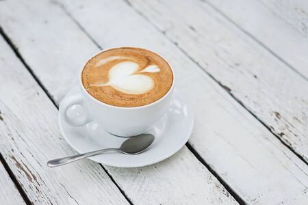 White big cup of delicious coffee with shaped heart art on white wooden table with copy space. Top view.の写真素材