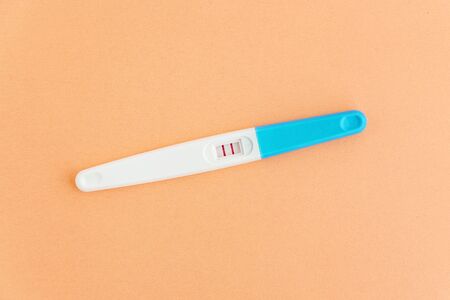 Positive pregnancy test on orange background. Planning of pregnancy, trying to have baby.の写真素材