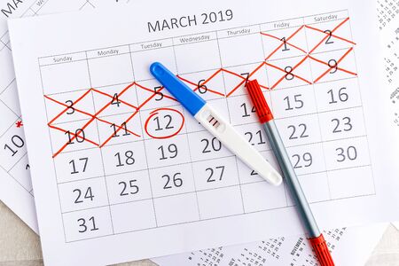 Positive pregnancy test with circling date in calendar. Planning of pregnancy, trying to have baby.の写真素材