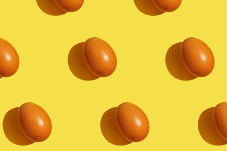 Brown eggs pattern on yellow background. Creative layout. Top view.の写真素材