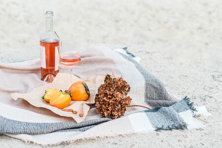 Picnic on the beach with persimmons, almond and bottle of rose wine on beige blanket. Lifestyle view.の写真素材