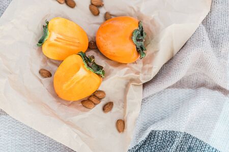 Picnic on the beach with persimmons, almond and bottle of rose wine on beige blanket. Lifestyle view.の写真素材