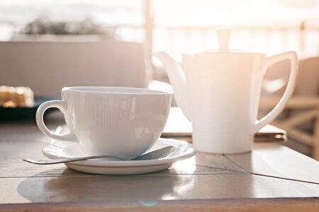White big cup of delicious coffee on wooden table in sunset light with copy space. Lifestyle view.の写真素材