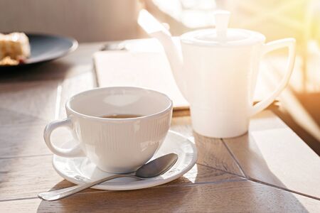White big cup of black tea on wooden table in sunset light with copy space. Top view.の写真素材