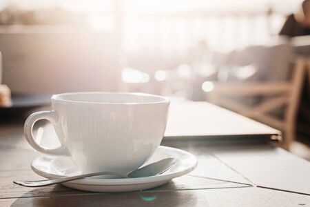White big cup of delicious coffee on wooden table in sunset light with copy space. Lifestyle view.の写真素材