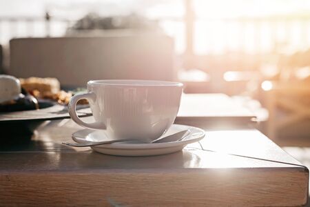 White big cup of delicious coffee on wooden table in sunset light with copy space. Lifestyle view.の写真素材