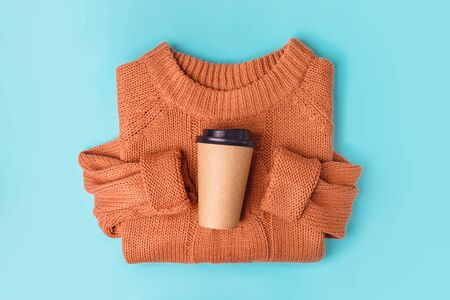 Coffee paper cup on orange knitted sweater background, top view flat lay. Take away coffee cup. Mockup.の写真素材