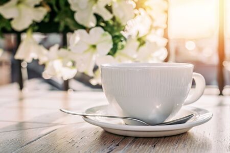 White big cup of delicious coffee on wooden table in sunset light with copy space. Lifestyle view.の写真素材