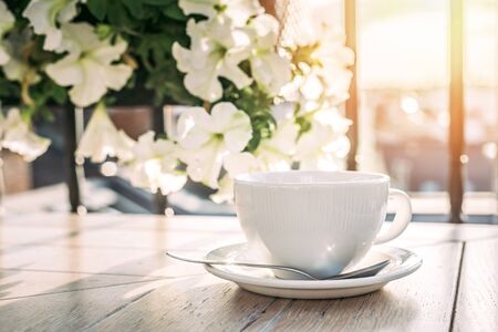 White big cup of delicious coffee on wooden table in sunset light with copy space. Lifestyle view.の写真素材