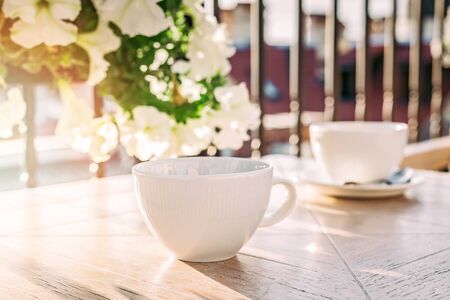 White big cup of delicious coffee on wooden table in sunset light with copy space. Lifestyle view.の写真素材