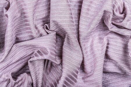 Violet shiny striped and crumpled fabric, abstract background. Close-up, top view.の写真素材