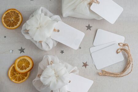 Christmas presents wrapped with white furoshiki fabric, labels and dried orange slices. Eco friendly gift, zero waste concept.の写真素材