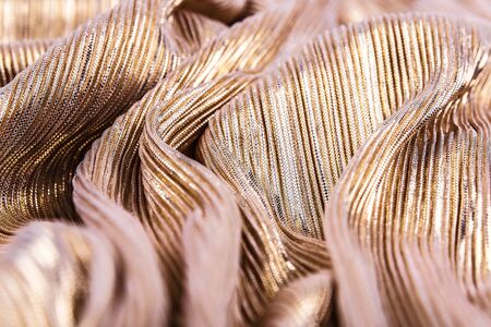 Golden shiny striped fabric, abstract background. Close-up, waves.の写真素材