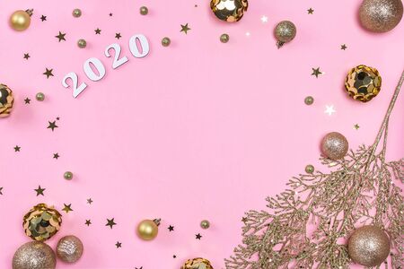 Festive christmas frame made of golden balls, fir tree branches, decorations and confetti on pastel pink background with copy space. Flat lay, top view. Christmas, winter, New Year concept.の写真素材