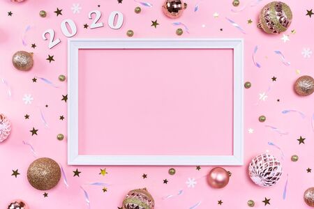 Festive christmas frame made of golden balls, fir tree branches, decorations and confetti on pastel pink background with copy space. Flat lay, top view. Christmas, winter, New Year concept.の写真素材