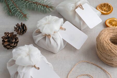 Christmas presents wrapped with white furoshiki fabric, labels and dried orange slices. Eco friendly gift, zero waste concept.の写真素材