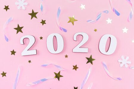 Wooden 2020 numbers and Christmas decorations, confetti, stars and snowflakes on pale pink background. Flat lay, top view.の写真素材