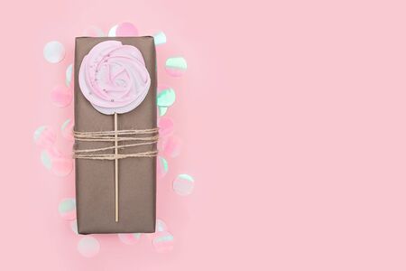 Present wrapped in craft paper with meringue candy decoration and holographic confetti. Holiday zero waste concept. Copy space.の写真素材