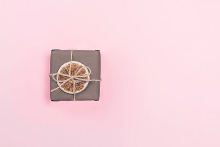 Present wrapped in craft paper with dried orange slice decoration. Flat lay, copy space. Holiday zero waste concept.の写真素材