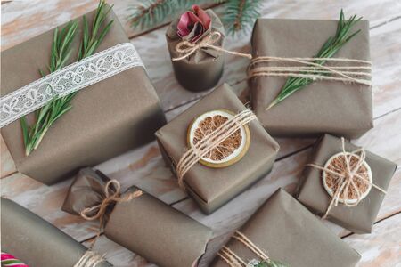 Pile of presents and gifts wrapped in craft paper with decoration on white wooden background. Flat lay, close up. Holiday zero waste concept.の写真素材