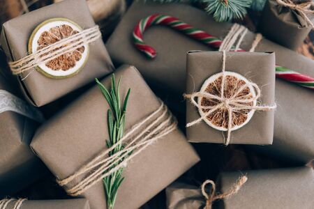 Presents and gifts wrapped in craft paper with decoration on brown wooden background. Flat lay, close up. Holiday zero waste concept.の写真素材