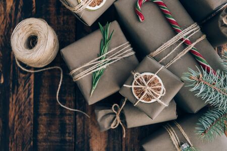 Presents and gifts wrapped in craft paper with decoration on brown wooden background. Flat lay, close up. Holiday zero waste concept.の写真素材