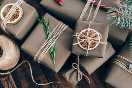 Presents and gifts wrapped in craft paper with decoration on brown wooden background. Flat lay, close up. Holiday zero waste concept.の写真素材