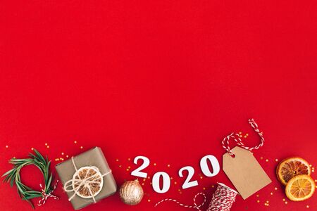 Christmas handmade garland made of 2020 wooden numerals and fir tree branches and other christmas decorations on red background. Christmas, New Year, zero waste concept.の写真素材