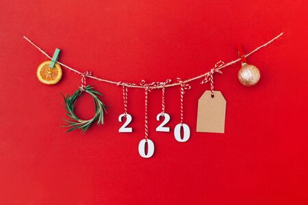 Christmas handmade garland made of 2020 wooden numerals and fir tree branches and other christmas decorations on red background. Christmas, New Year, zero waste concept.の写真素材