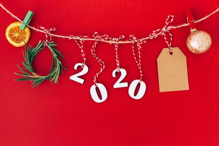 Christmas handmade garland made of 2020 wooden numerals and fir tree branches and other christmas decorations on red background. Christmas, New Year, zero waste concept.の写真素材