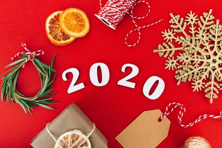 Wooden 2020 numbers and Christmas decorations on red background. Flat lay, close up. Holiday zero waste concept.の写真素材