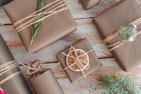 Pile of presents and gifts wrapped in craft paper with decoration on white wooden background. Flat lay, close up. Holiday zero waste concept.の写真素材