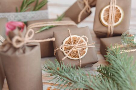 Pile of presents and gifts wrapped in craft paper with decoration on white wooden background. Flat lay, close up. Holiday zero waste concept.の写真素材