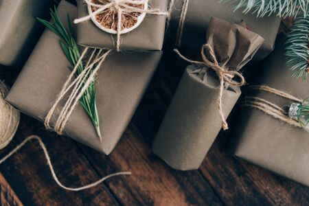 Presents and gifts wrapped in craft paper with decoration on brown wooden background. Flat lay, close up. Holiday zero waste concept.の写真素材