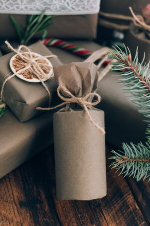 Presents and gifts wrapped in craft paper with decoration on brown wooden background. Flat lay, close up. Holiday zero waste concept.の写真素材