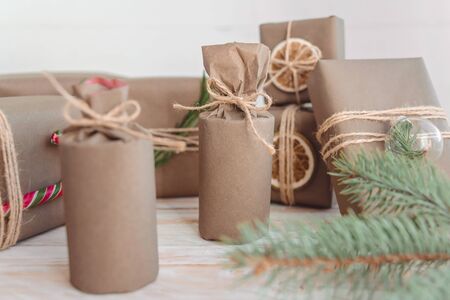 Pile of presents and gifts wrapped in craft paper with decoration on white wooden background. Flat lay, close up. Holiday zero waste concept.の写真素材