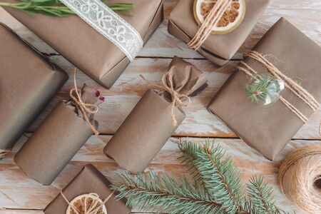 Pile of presents and gifts wrapped in craft paper with decoration on white wooden background. Flat lay, close up. Holiday zero waste concept.の写真素材